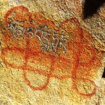 A red ochre Bon endless knot upon which the Buddhist mani mantra was carved