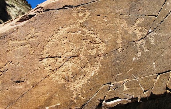 Fig. 13. Although all the Upper Tibetan mascoids thus far depicted in this newsletter appear to date to the Iron Age or perhaps in certain cases to the Bronze Age, cruder examples from later times are also encountered. In this image we see a mascoid with typical regional features (legs, complex interior ornamentation and smaller upper circle). It is flanked by a wild herbivore and a standing anthropomorph. This more crudely rendered mascoid was carved with shallow lines and has not undergone as much repatination as others we have examined. As is other rock art in the close vicinity, this composition is best dated to the protohistoric period (100 BCE–650 CE). The maker of this image must have gained inspiration from older mascoid art found in the area. Perhaps his carving was a tribute to distant ancestors and those things they held dear. 