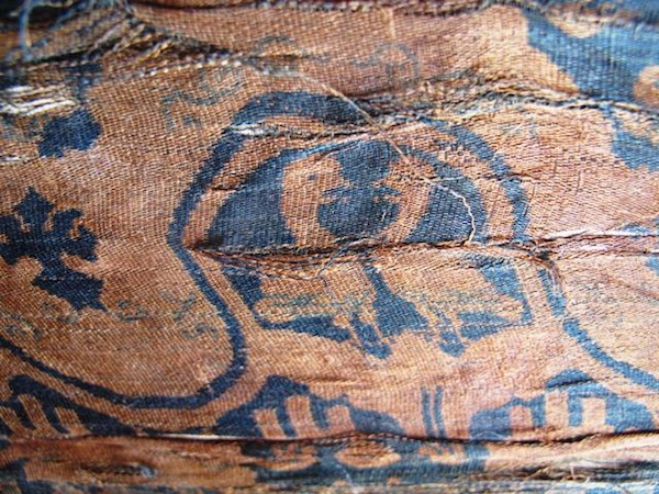 Fig. 2. A close-up view of confronted waterfowl woven in the Gurgyam silk. What appears to be a pair of ducks or geese stand within wave and floral-like purfle. These motifs are beige in color while the ground is a rich indigo blue.