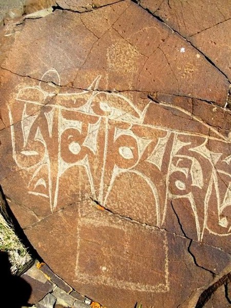 Fig. 14. The basal rock art consists of an archaic chorten with three tall tiers, small round bumpa and horn-like finial, northwestern Tibet. At a much later date the mani mantra was added smack over the middle of the chorten. This suggests that the chorten was made by those who followed archaic religious traditions, the mantra added as a kind of ritualized subjugation. This action needless to say bespeaks a certain zealotry.