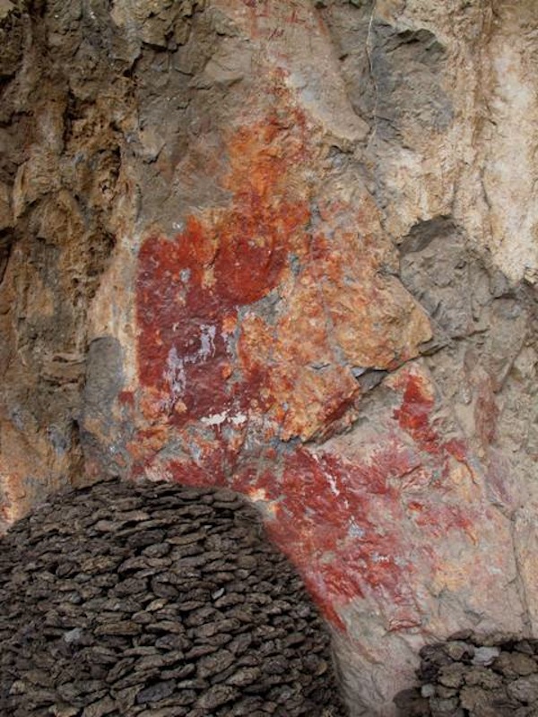 Fig. 1. The stacking of yak dung for fuel use partially obscures a giant red ochre pictograph of an archaic chorten, Lake Nam Tsho. This is just one of many recent impingements on the early artistic heritage of this history laden region. Pictured is the largest pictograph discovered to date in Upper Tibet.