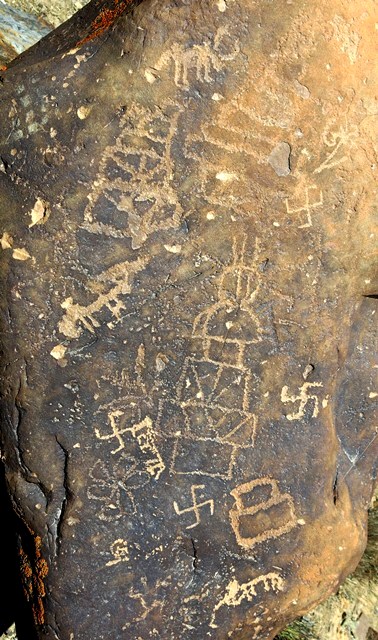 Fig. 67. Three stepped shrines probably of the Protohistoric period and a fully developed chorten (35 cm high) of the Early Historic period, Dzamathang. The three older ceremonial structures are of types (stylistically and technically) we have already examined. Near the top of the photograph is a wild yak exhibiting similar wear and re-patination qualities. A more refined technique of engraving was used to produce the chorten. Below the bumpa is a half-circle layer and below that four rectangular layers. One level is segmented by straight and diagonal lines and another level by diagonal lines only. Above the bumpa extend three vertical lines. A flower of six petals was engraved with the same technique as the chorten. By its paleographic characteristics, an inscribed Om in the upper left hand side side of the photograph was produced either in the Early Historic or Vestigial period. The four swastikas are of more recent production.