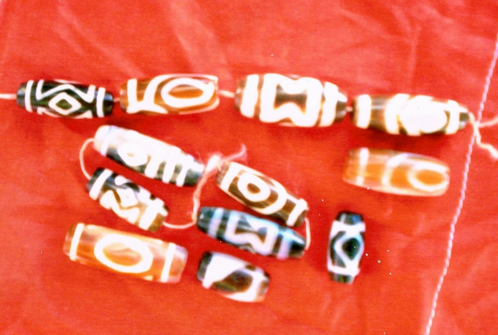 Fig. 5. Ancient patterned chalcedony (agate, onyx, etc.) and possibly carnelian beads recovered from tombs at Gyu. The white line or lines circumscribing the ends of most of the beads are known as ‘mouth design’ (kha-ris). The oval and diamond patterns are called ‘water eye’ (chu-mig, a name for springs in Tibetan, which according to Tibetan folklore, are from where many zi originate). The design consisting of an hourglass pattern opposite an eye is called ‘sky portal, earth portal’ (sa-sgo gnam-sgo). Photo courtesy of SRAHS (unfortunately, the photos made available are somewhat out of focus).