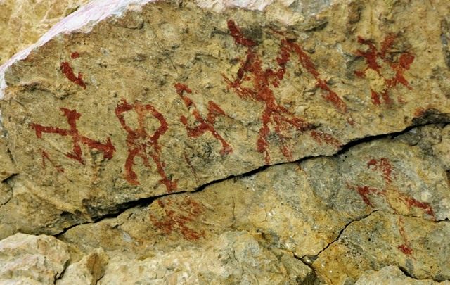 Fig. 25.2. A close-up of pictographs on the left end of the rock ceiling, Kubum. The anthropomorph appears to be depicted with a linear object in one hand and male genitalia (common in the rock art of Spiti). Note the primitive swastika below the sunburst.