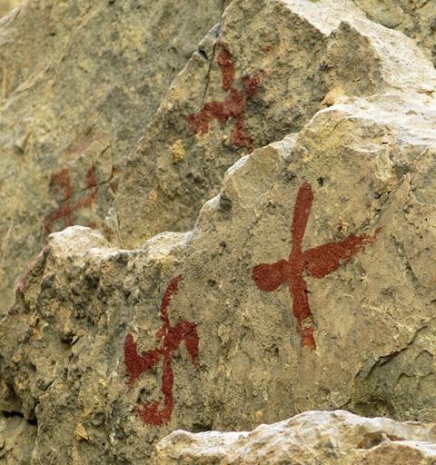 Fig. 25.6. Three red ochre swastikas and cruciform painted on a cliff face near the rock ceiling, Kubum.