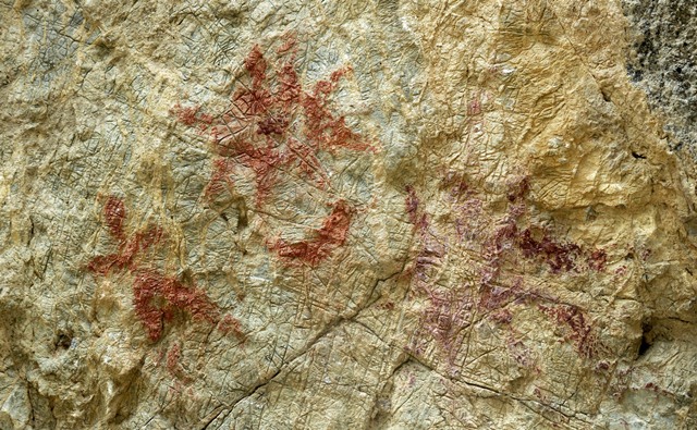 Fig. 26.5. Pictographs on the rock face of Thonsadrak 2. From left to right: anthropomorph, sunburst, crescent moon, and sunburst. The darker red ochre sunburst on the right was made on a different occasion. Nevertheless, these respective compositions complement one another.