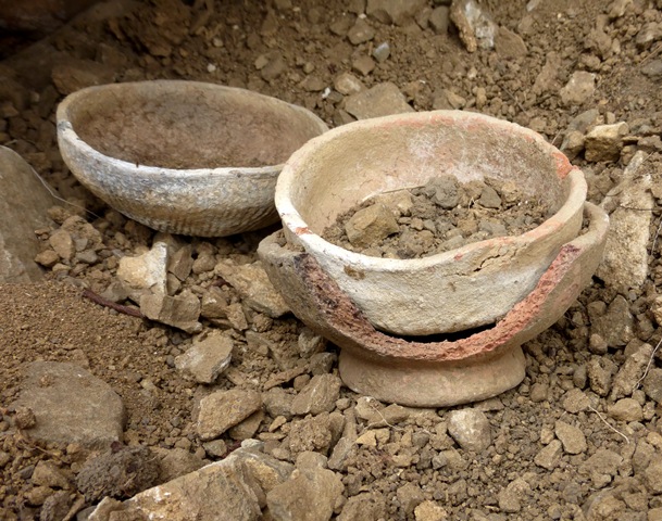 Fig. 38. Three ceramic bowls from the tomb in fig. 36. The broken bowl with a wide pedestal and the lighter colored bowl it cradles are smooth walled. The conical bowl in the background is cord marked. The coarse texture of these kinds of funerary ceramics is clearly visible along the break in the footed bowl. Photo courtesy of SRAHS.