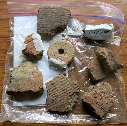 Fig. 50. Various ceramic fragments and ceramic spindle whorl collected around Chichim village. Some of these sherds may be from mortuary vessels. The whorl may have come from the grave of a female.