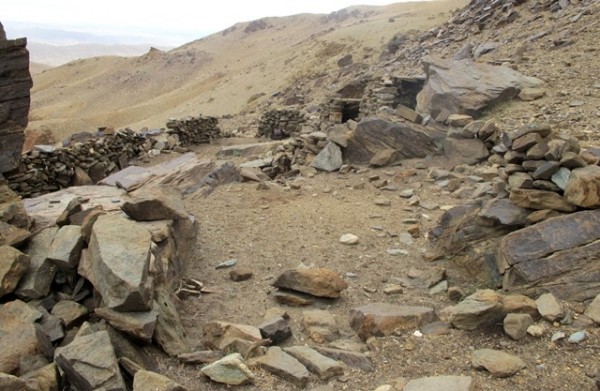 Fig. 2. Rock Art Village with the badlands of Guge in the background. The level area in the foreground was once part of an upper tier residence now levelled to the ground. On the large boulders surrounding the flat patch are various petroglyphs. In the middle of the photo are stone roof members resting on structures belonging to the middle and upper tiers of the site.