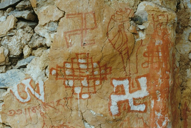 Fig. 54. Bichrome counterclockwise swastika, syllable A and two endless knots (pa tra), as well as a red ochre swastika and conch. Located on same structure as paintings in fig. 53. Circa 900–1200 CE. The letters are part of the beginning of a mantra for the Yungdrung Bon god Shenlha Ödkar (Gshen lha ’od dkar).