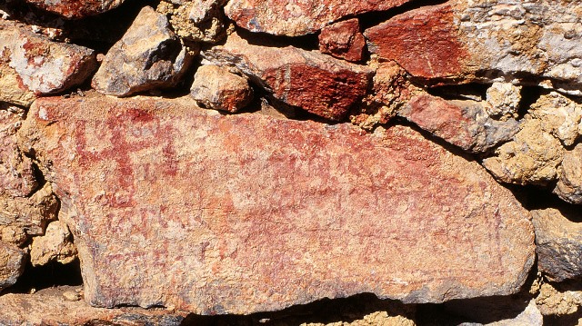 Fig. 71. Clockwise swastika painted over part of the Yungdrung Bon mantra for the god of boundless light, Shenlha Ökar, western Changthang. These red ochre inditements occur on the main foundation stone of a ruined hermitage (also see figs. 53–55). Vestigial period.