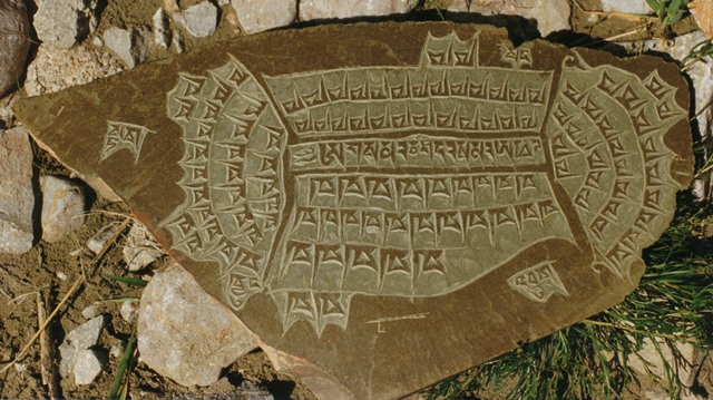 Fig. 1. An adeptly carved in relief stone plaque with the mantra of 14 syllables occupying the center, surrounded by rows of the Tibetan letter kha, adding up to 108 in total. The names of the four warrior spirits of the lungta are arrayed around all but the right side of the plaque. The vowel sign (’greng-bu) over the word “lion” has broken off. Tshochen/Gertse.