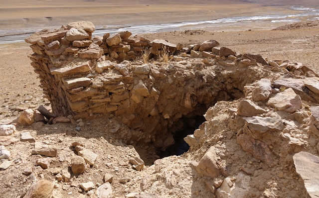 Fig. 37. The exposed east wall of the temple-tomb and excavation, Central Complex. This wall was adeptly constructed of slabs. The earth and stones removed from the center of the structure are fill added to the ruin sometime in the past.