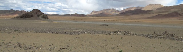 Fig. 19. The stelar necropolis viewed from the northwest. The temple-tomb studded with pillars and the companion structure (Mound II) are on the right side of the image. To their left is a rocky dispersion with remnants of structures. A mani wall with inscribed Buddhist plaques is in the middle of the image, while the pyramidal formation of Thangde Mukyu can be seen off to the left.