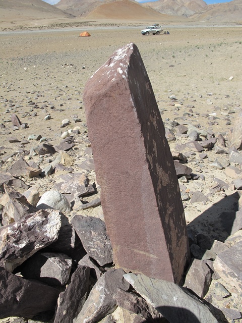 Fig. 32. A close-up of one of the red sandstone pillars erected atop the temple-tomb mound. Although the pillar itself appears to be ancient, its current placement is a later modification to the site. The author’s camp is in the background.