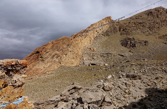 Fig. 1. The mouth of the defile in which Gondak is located. Prayer flags have been strung across this sacred site by local villagers. The ruins are at the base of the orange formation and two-thirds of the way up its inner (right) side.