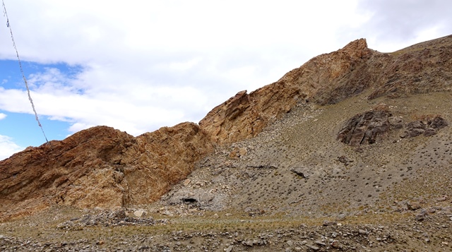 Fig. 2. The shrine complex on a bench (foreground) and ruins of the upper residential complex on slope paralleling the middle reaches of the orange rock formation, a tall rib of limestone. The dark-colored outcrop in the middle of the slope (right side of photograph) also hosted residential structures.