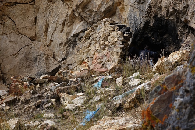 Fig. 26. A partial view of the façade and mouth of the larger cave on the top end of the upper tier of the upper residential complex. The standing wall is of more recent construction, while the jutting base of the wall was once part of an archaic era structure.