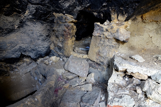 Fig. 27. Masonry and mud platform (right), walled cubbyhole (middle) and berm around the opening of a basement (left) found inside the cave illustrated in fig. 26. Note the stone slab forming the roof of the basement around the opening in the floor.